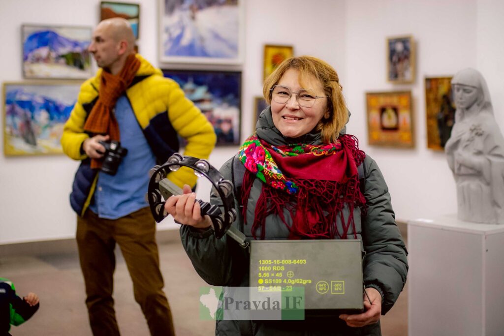 Люди в галереї, жінка тримає бубон і коробку.