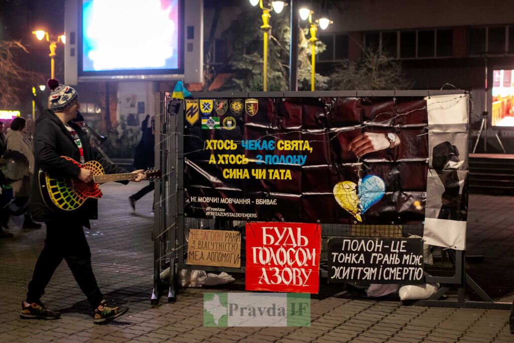 Музикант грає перед банером на вулиці.