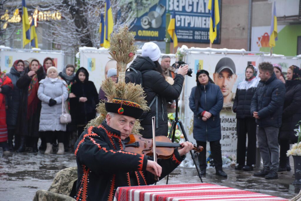 Скрипаль у національному одязі на вулиці взимку.