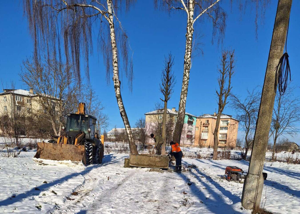 Трактор прибирає сніг біля будинків взимку.