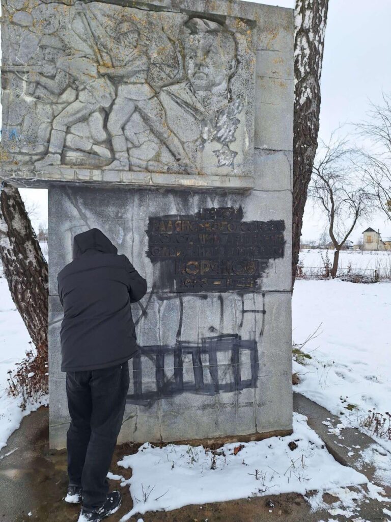 Людина біля бетонного пам'ятника взимку.