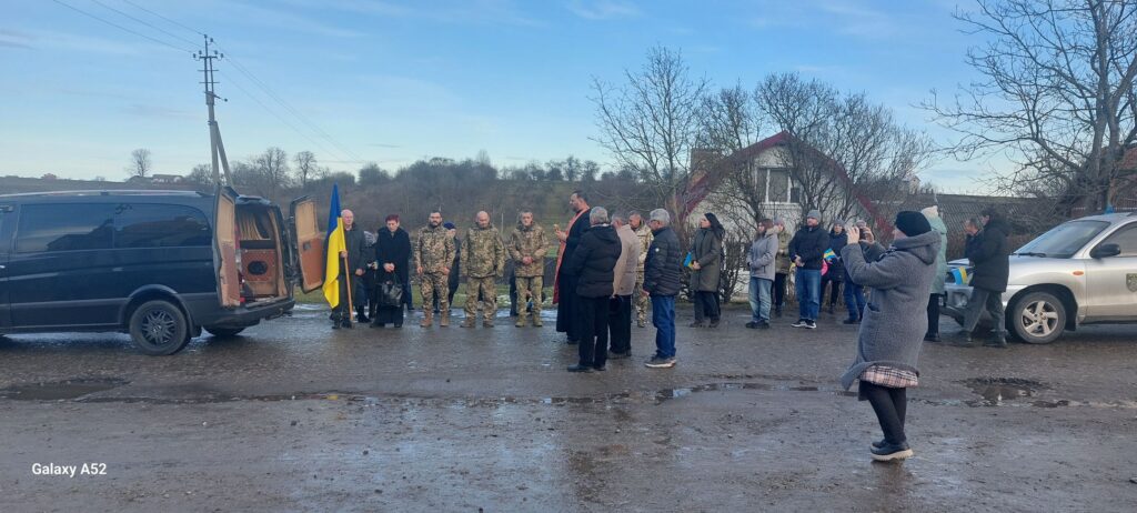 Люди з українським прапором біля чорного автомобіля