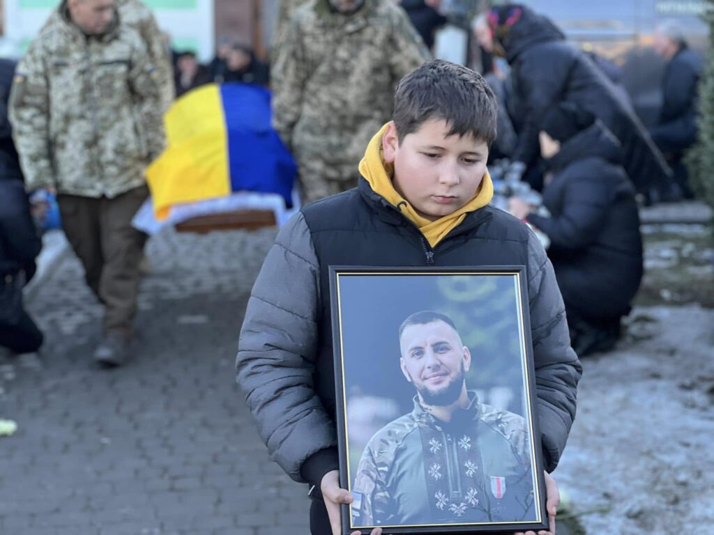 Дитина з портретом загиблого військового в Україні