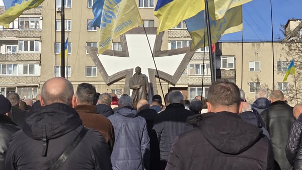 Протест біля пам'ятника з прапорами на фоні.