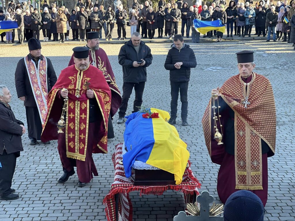 Церемонія похорону з українським прапором на труні.