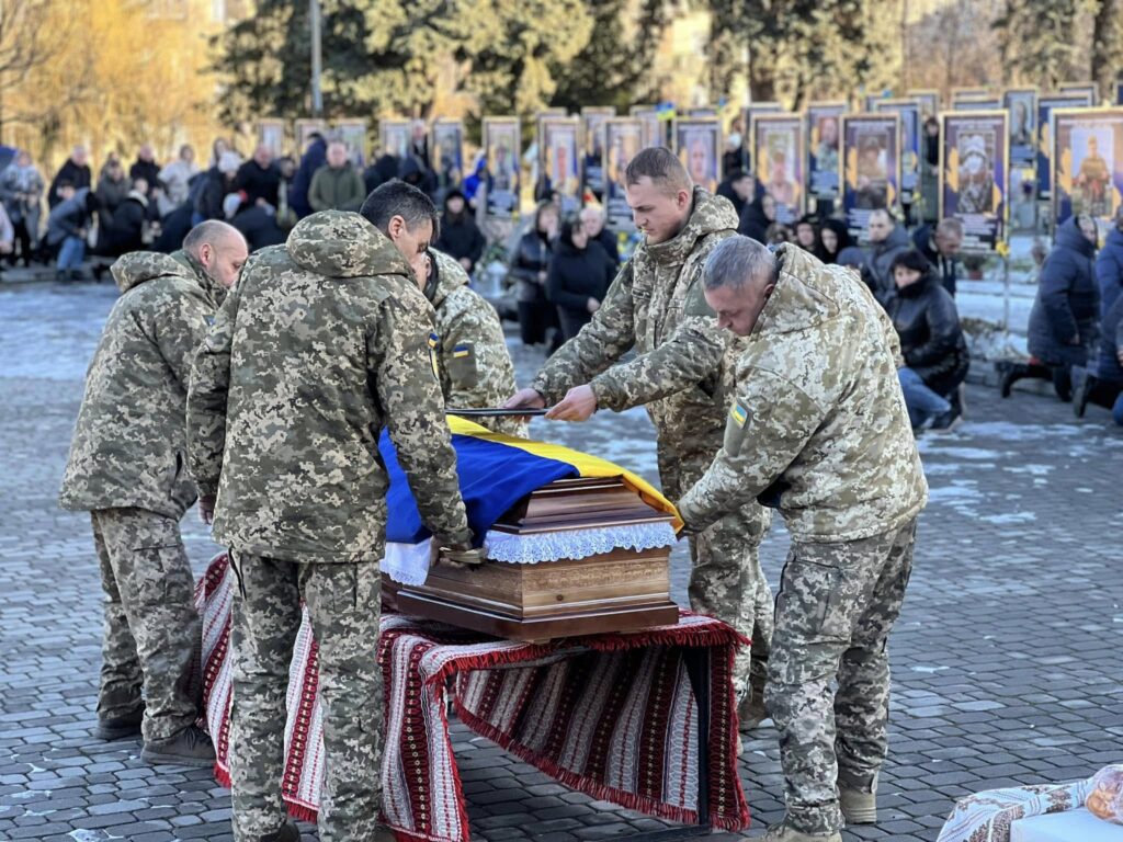 Військові несуть труну під прапором України.