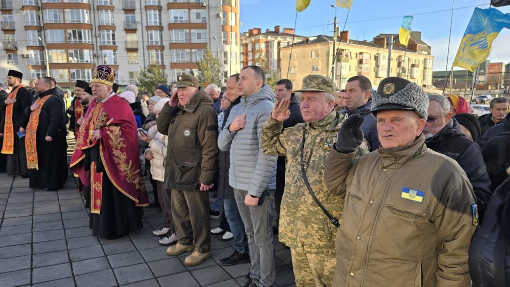 Учасники церемонії біля будівлі з прапорами України