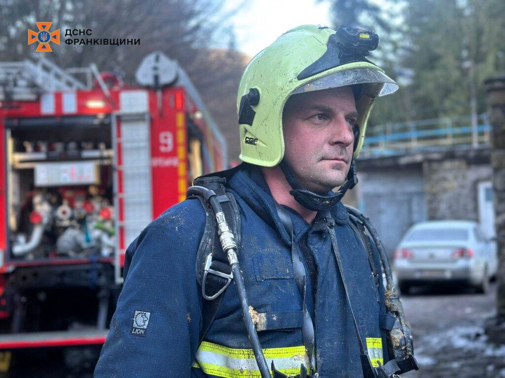 Пожежник у захисному шоломі з пожежною машиною