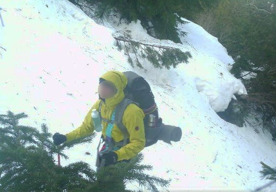 Турист у жовтому куртці на засніженій стежці