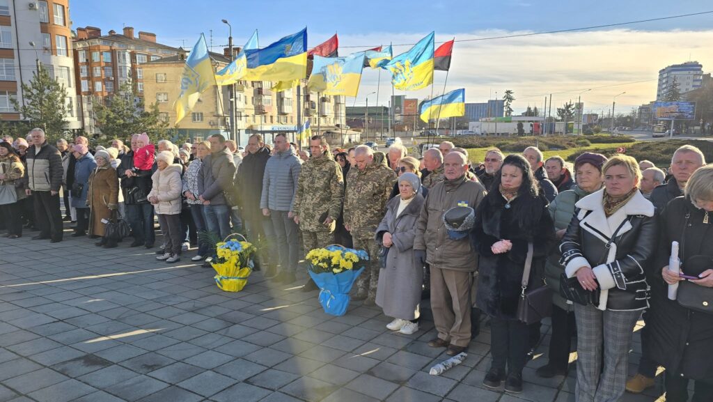 Люди на мітингу з українськими прапорами.