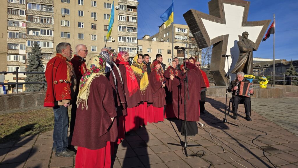 Український хор співає біля пам'ятника у місті.