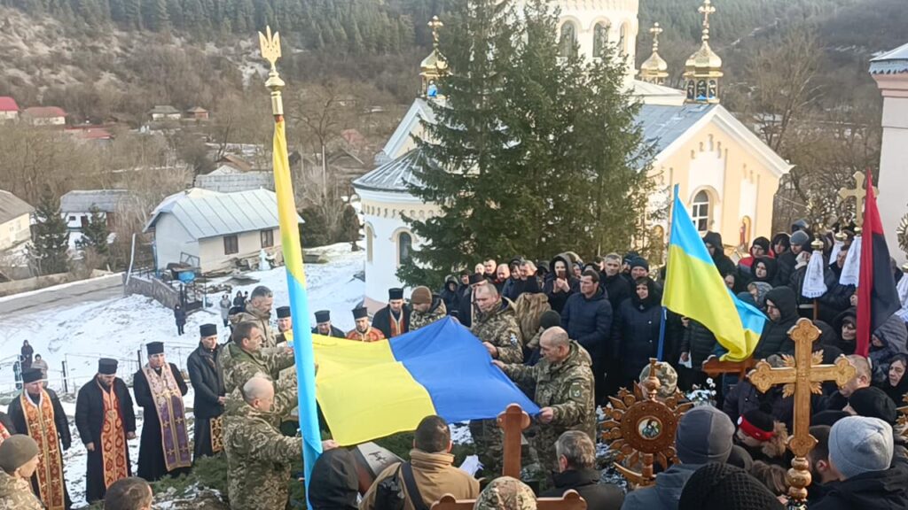 Церемонія з українським прапором біля церкви взимку.