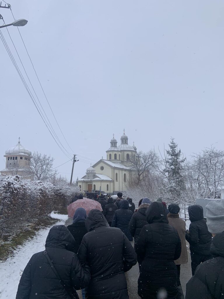 Люди йдуть до церкви взимку, сніг падає.