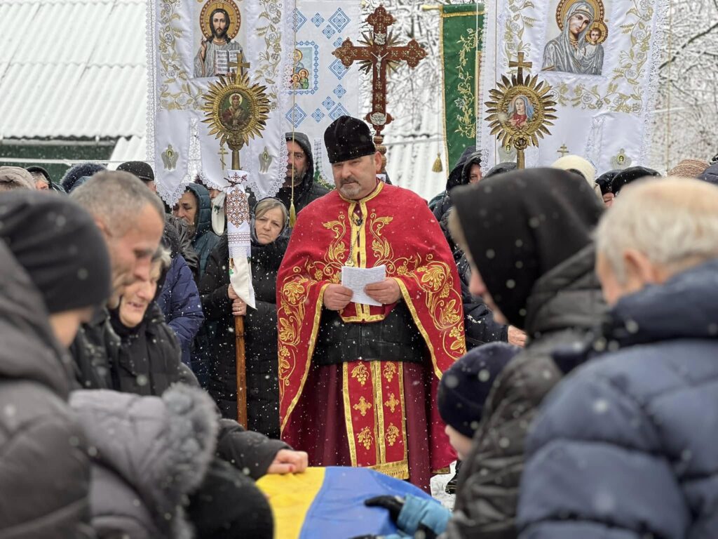 Люди на релігійному заході зі священиком взимку.