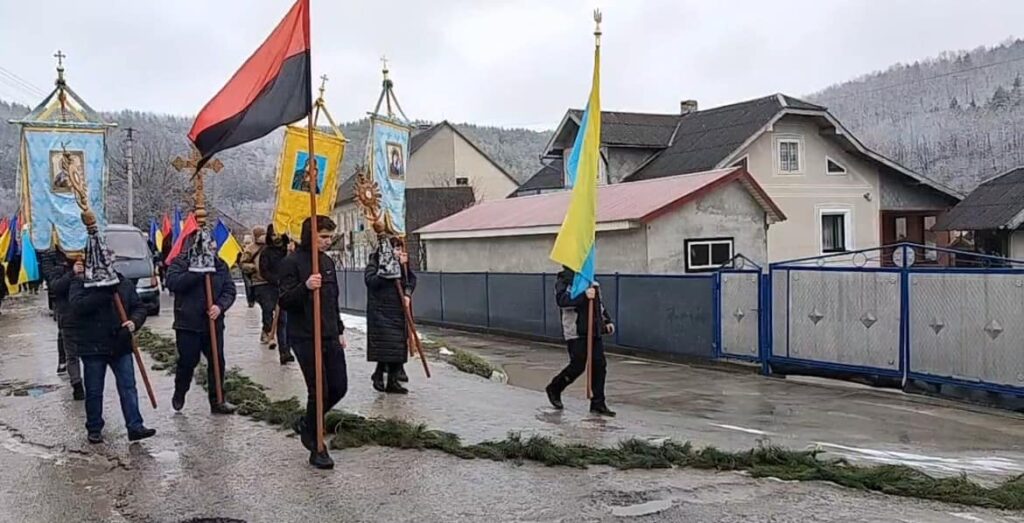 Люди з національними прапорами на вулиці в селі.