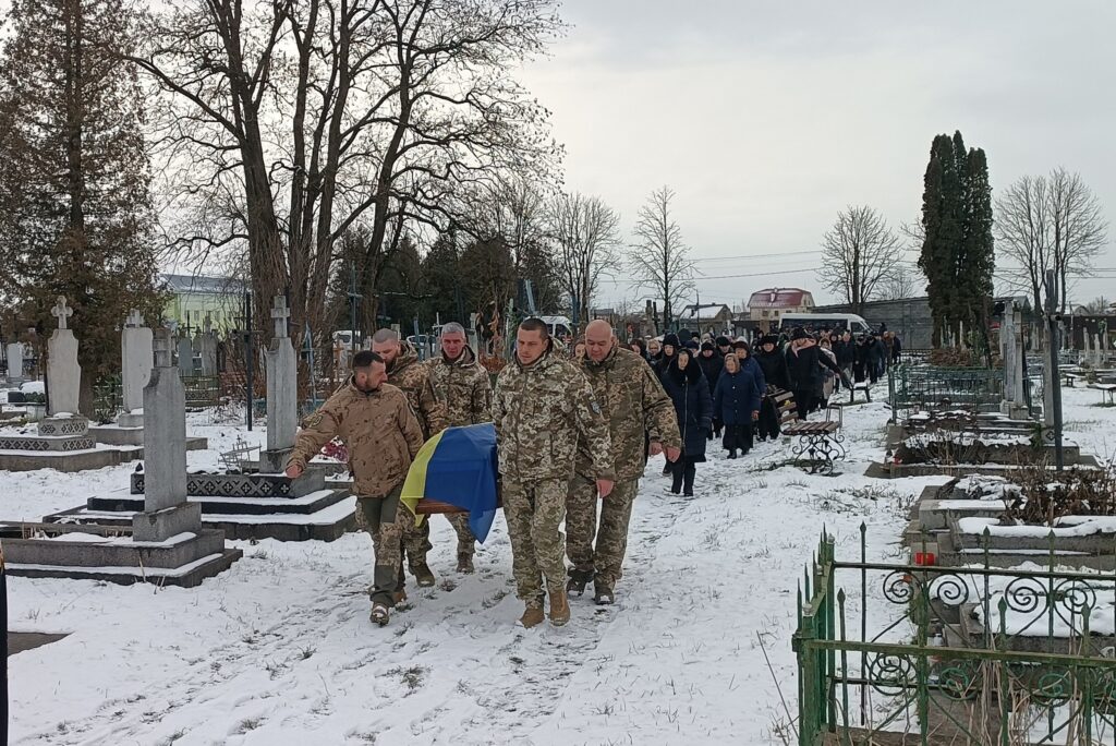 Похоронна процесія українських військових на цвинтарі взимку.