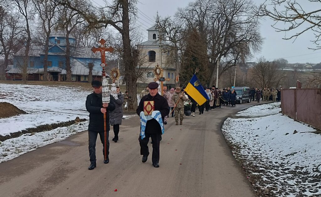 Релігійна процесія йде сільською дорогою взимку.