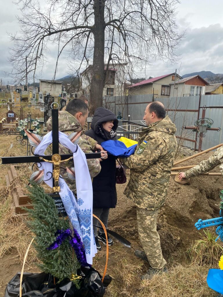 Військові передають прапор на кладовищі.