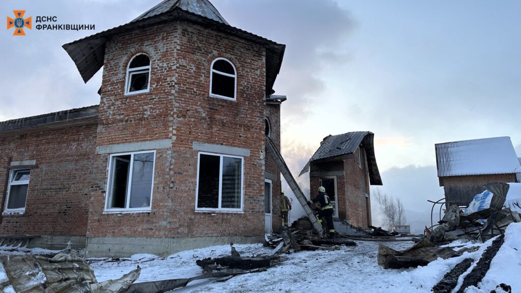 Пожежники працюють біля пошкодженого будинку взимку.