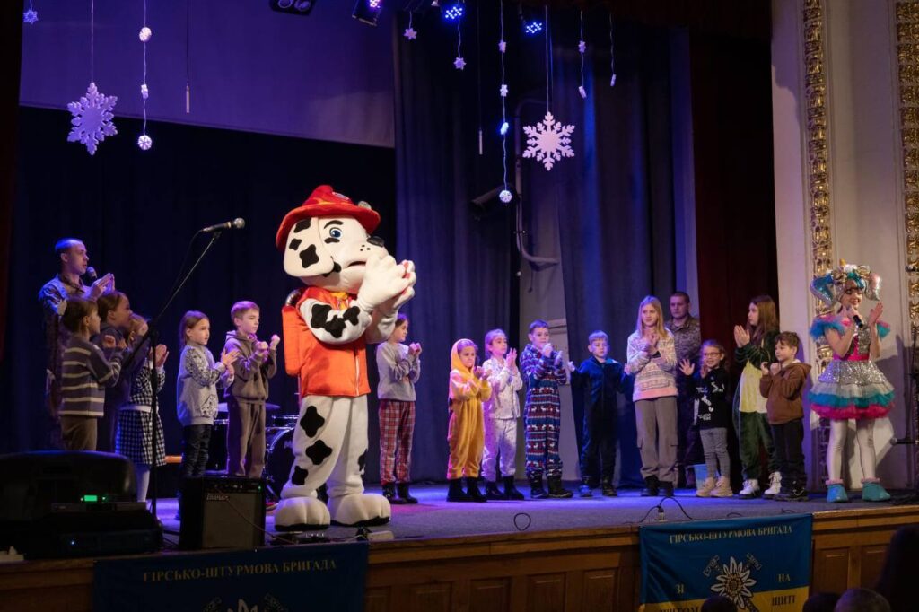 Діти на сцені з аніматором у костюмі персонажа.