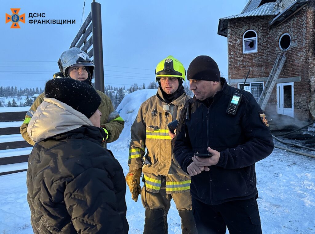 Рятувальники на засніженій місцевості біля пошкодженого будинку.