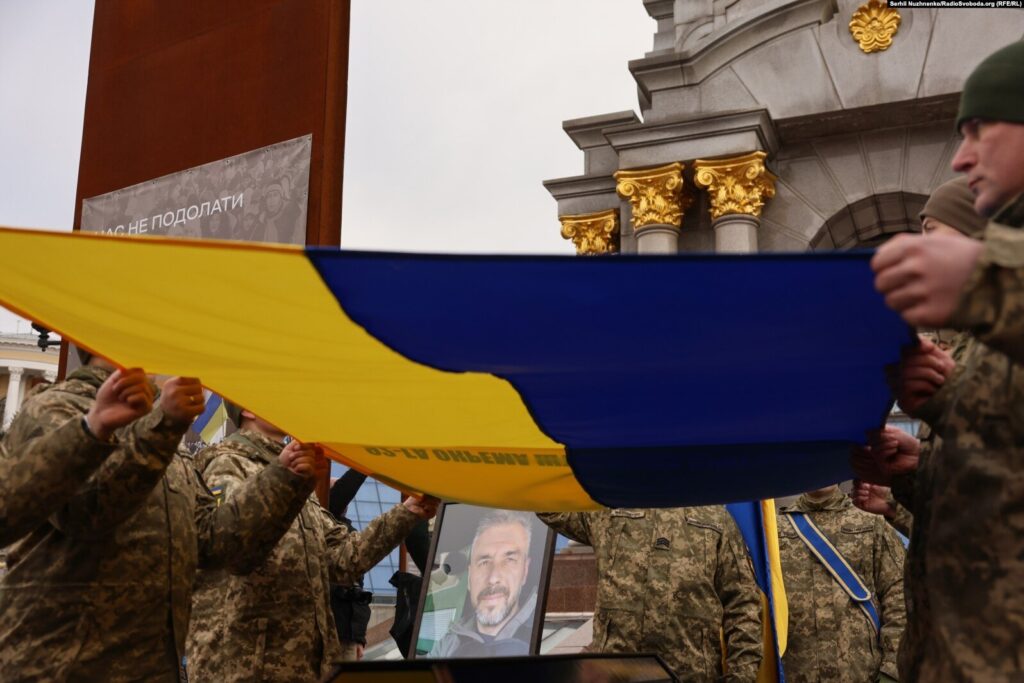 Військові тримають великий український прапор.