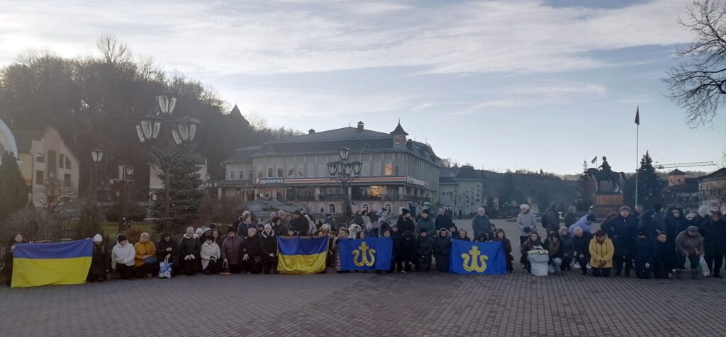 Люди з прапорами на площі перед будівлею.