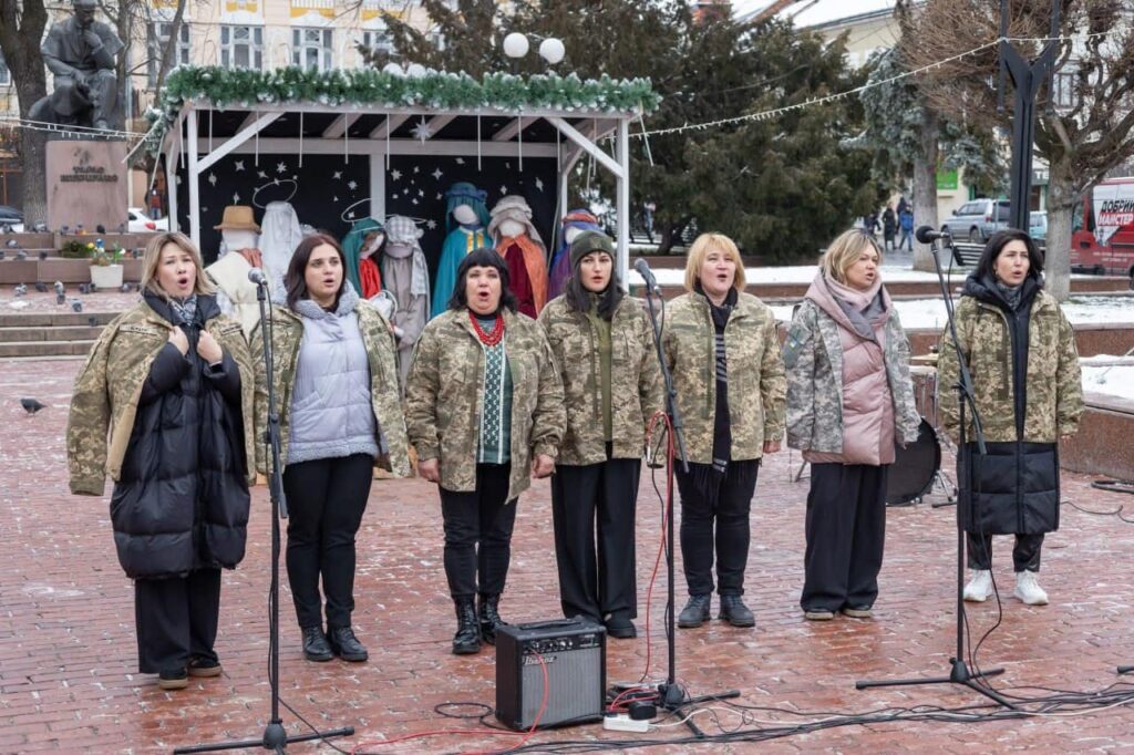 Жіночий хор у камуфляжі співає на вулиці.