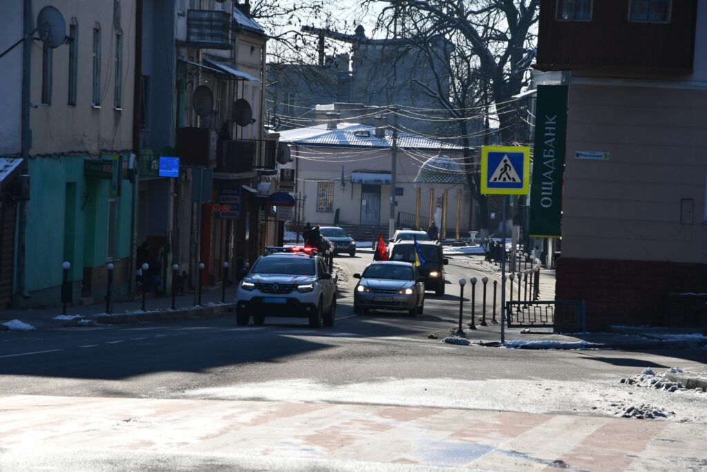 Зимова вулиця з автомобілем та пішохідним знаком.