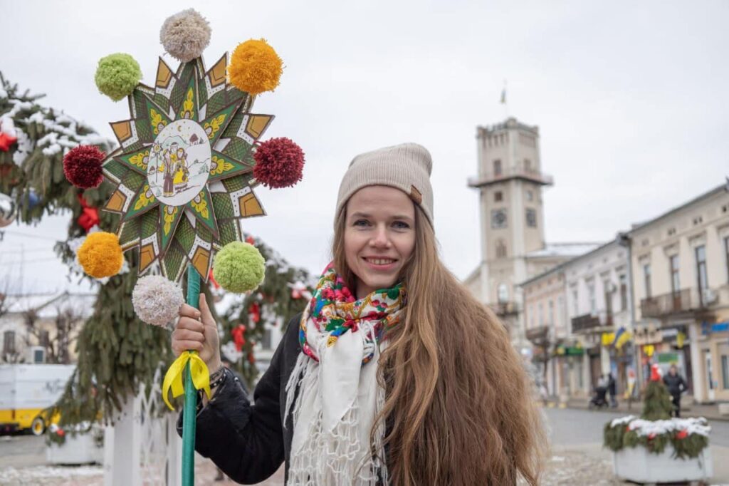 Жінка в зимовому одязі тримає різдвяну зірку.