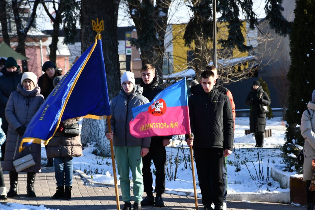 Молодь на заході з українськими прапорами взимку.