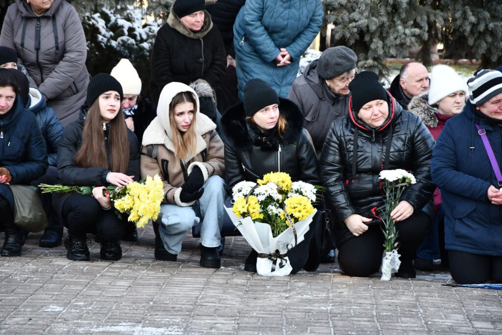 Люди сидять з квітами на вулиці взимку.