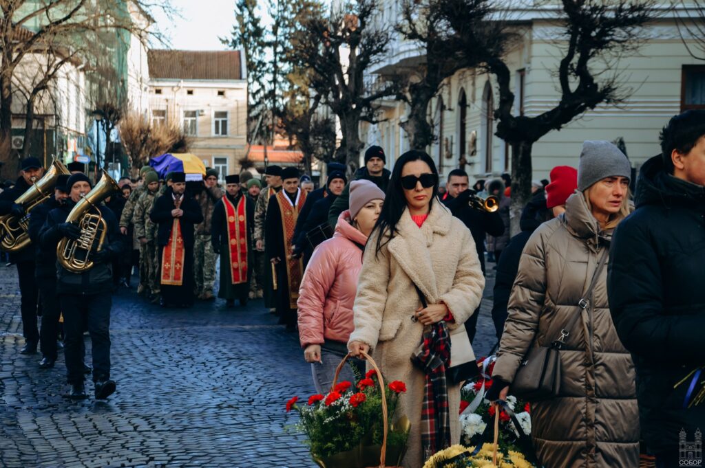 Церемонія поховання з оркестром і вінками на вулиці.