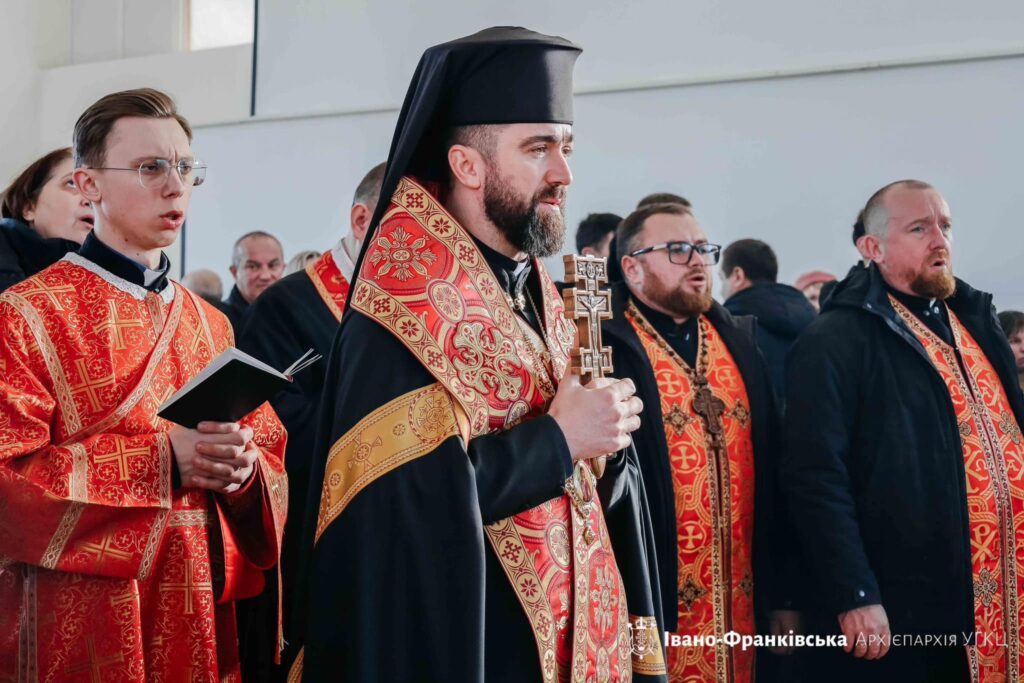 Священики у церкві з хрестом і молитвеником.