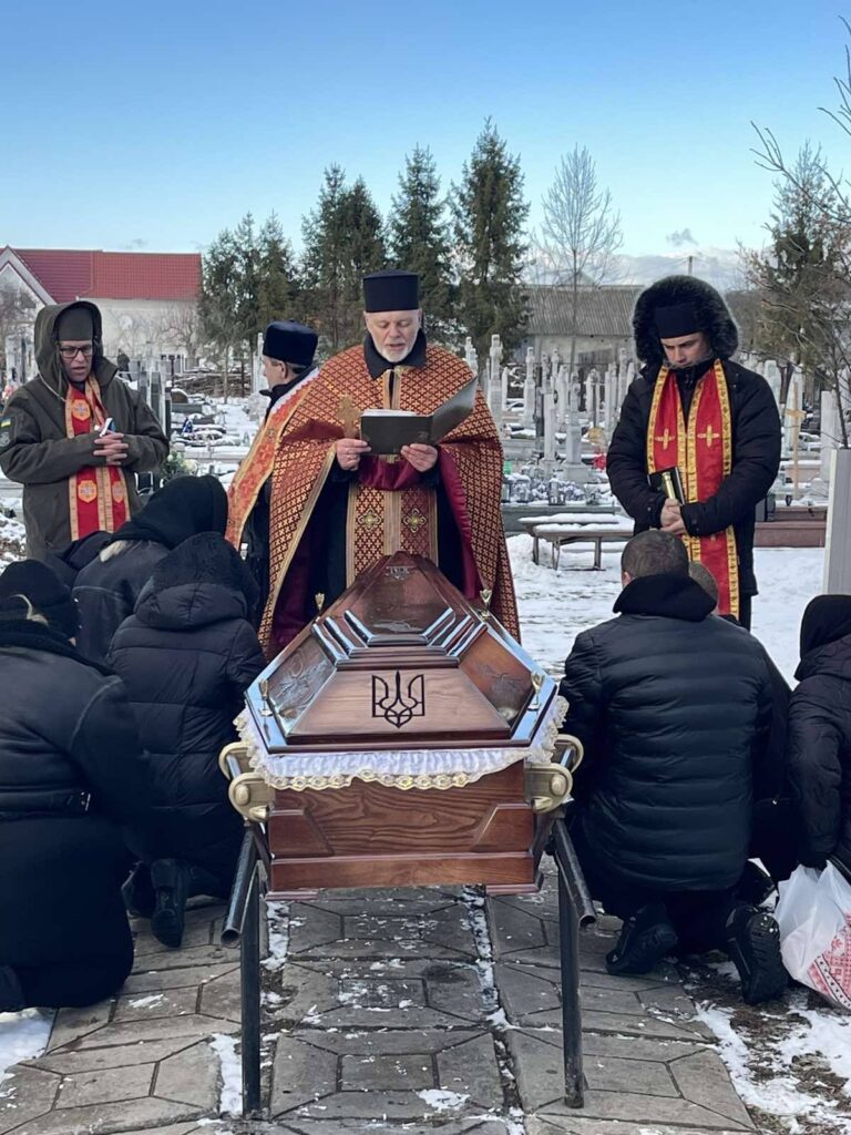 Церемонія поховання з духовенством на кладовищі взимку.