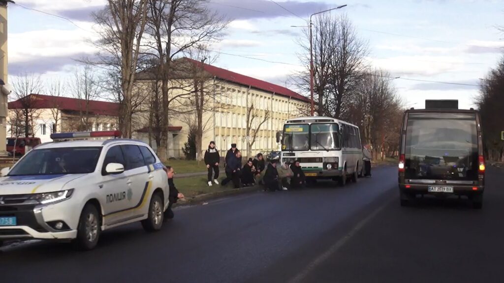 Поліцейський автомобіль, автобус і люди на узбіччі