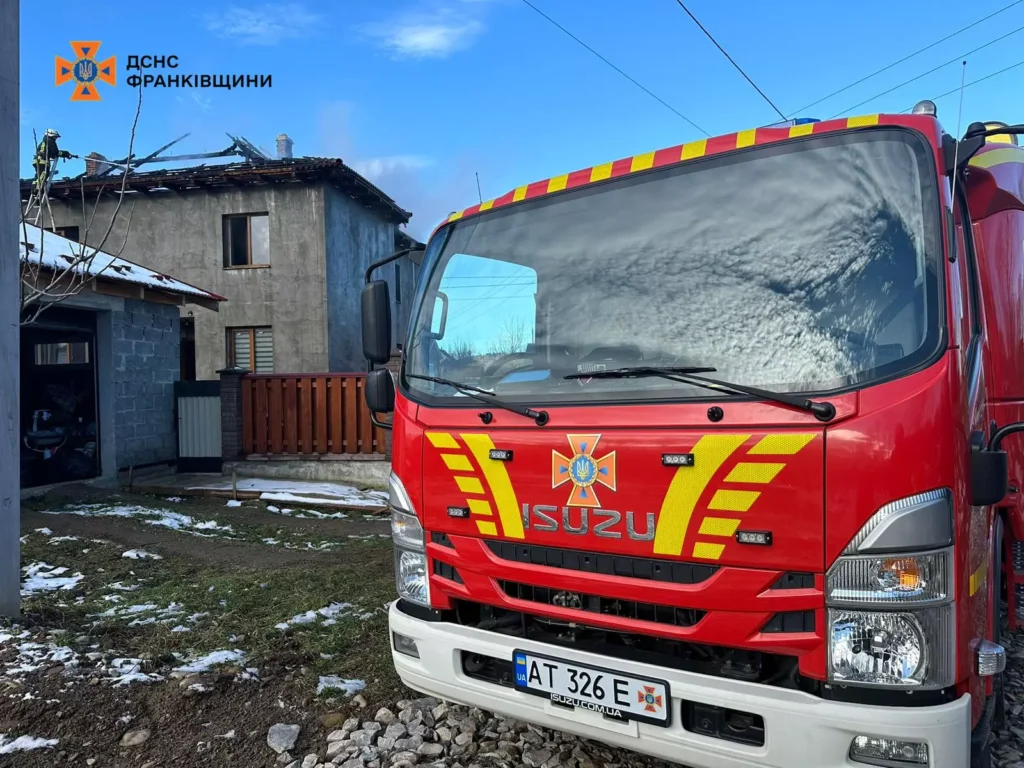 Пожежна машина біля пошкодженого будинку взимку.