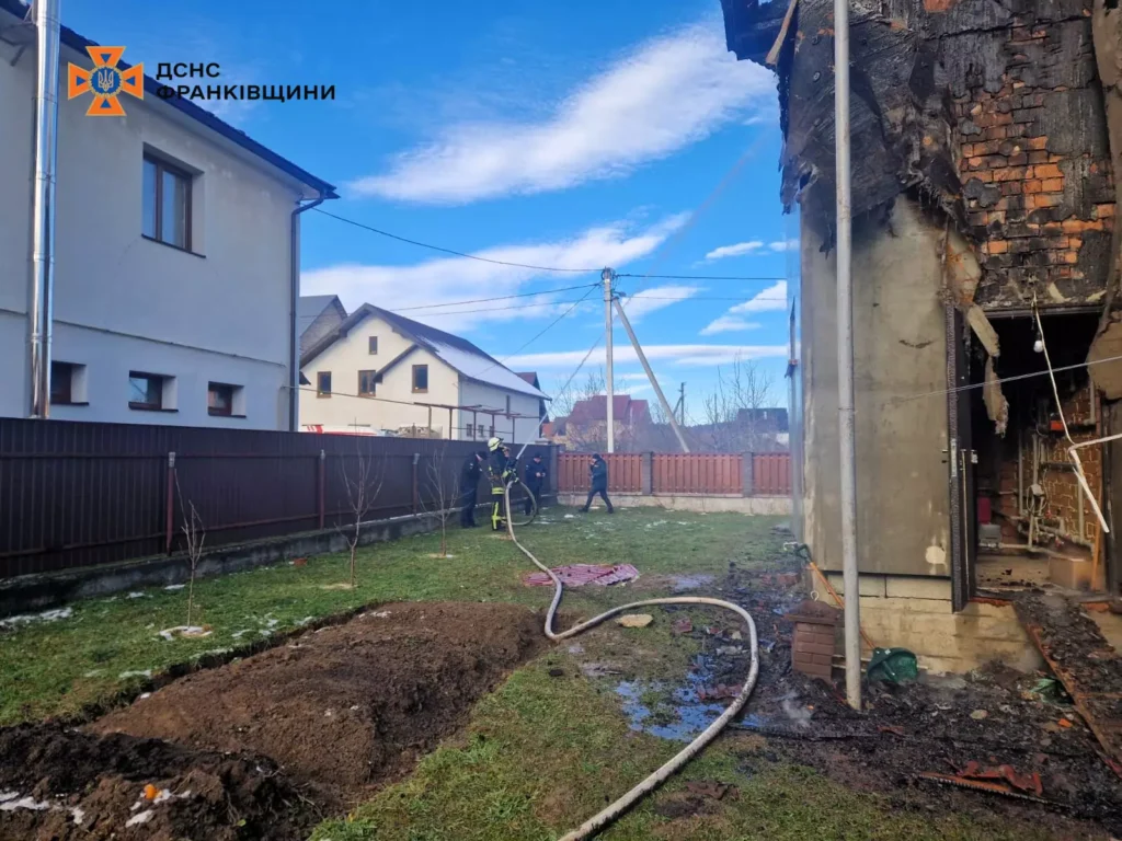 Пожежники ліквідують наслідки пожежі біля будинку.