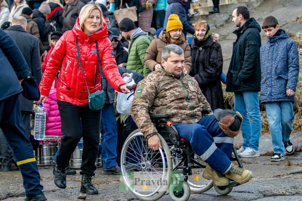 Чоловік у інвалідному візку серед натовпу людей