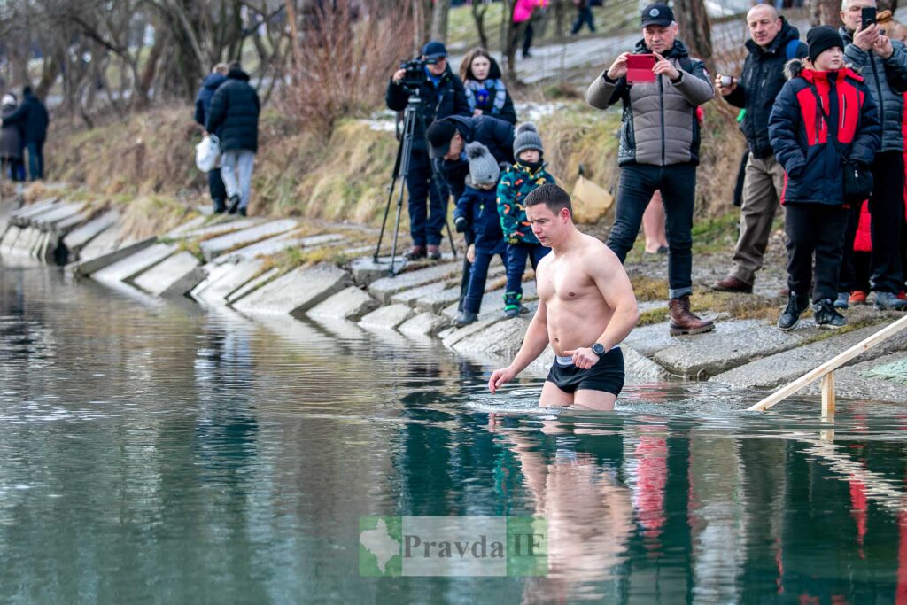 Чоловік входить у водойму серед натовпу глядачів.