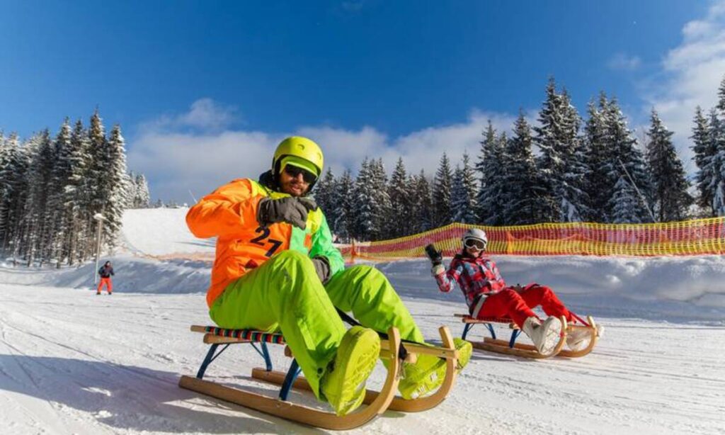 Люди катаються на санках засніженими схилами.