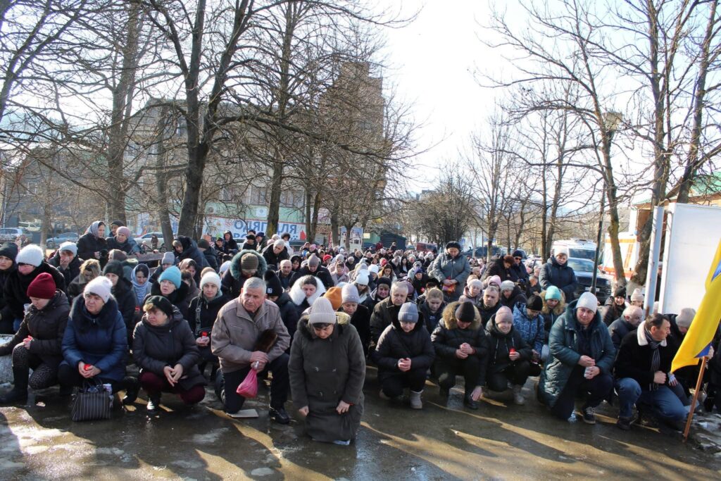 Люди на колінах в парку серед дерев