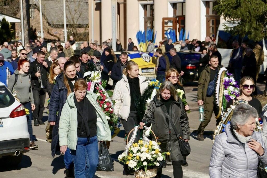 Люди несуть вінки на вуличній церемонії вшанування.