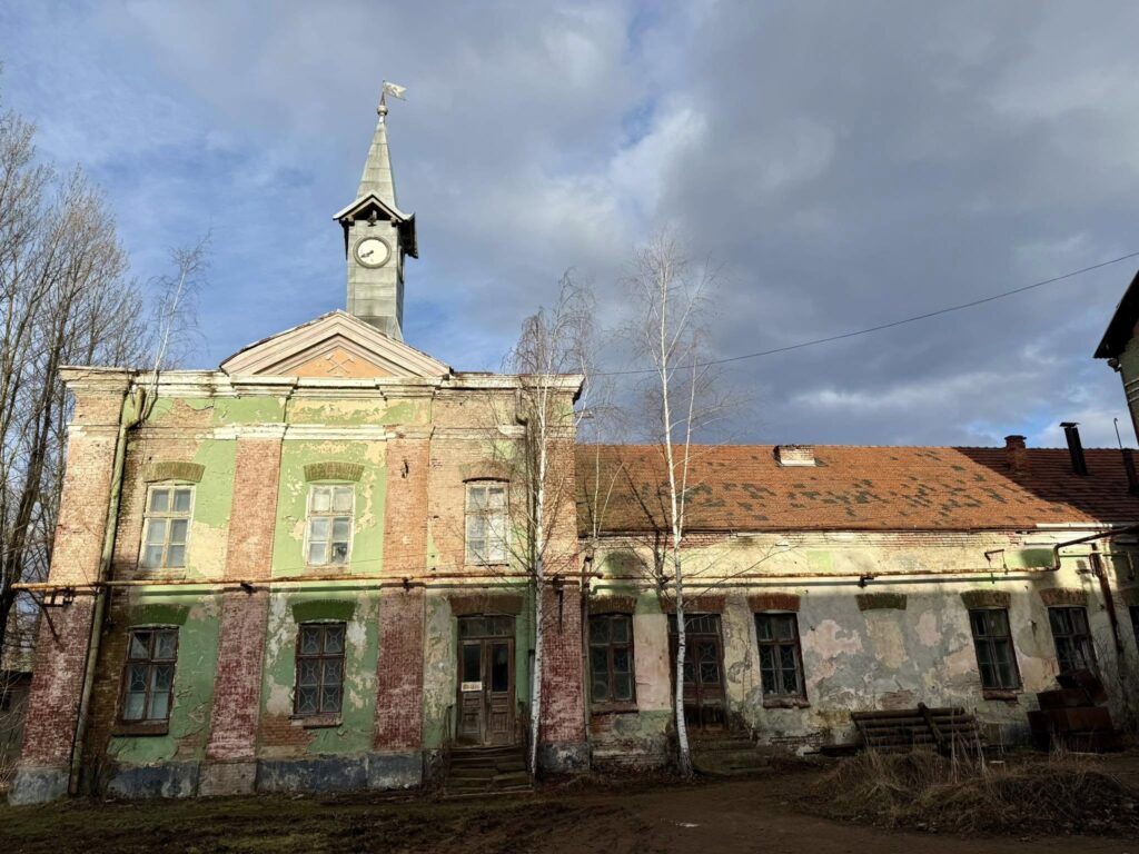 Старовинна будівля з вежею та годинником на фасаді.