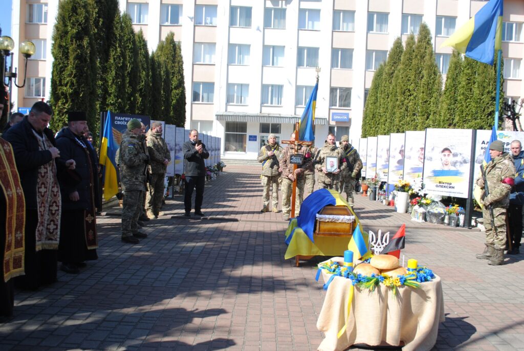 Пам'ятна церемонія українських військових із прапорами.