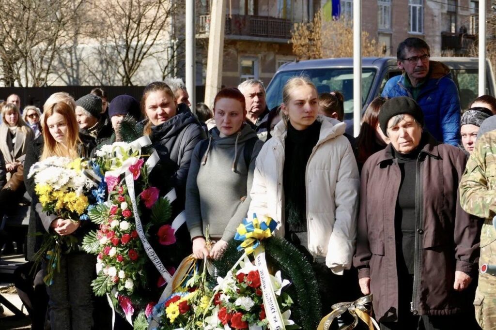 Люди з вінками на вулиці під час мітингу.