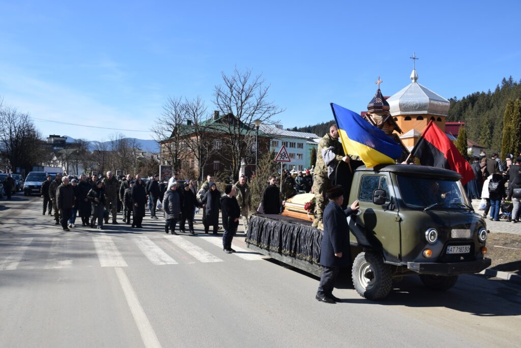 Похоронна процесія з українським прапором на авто.