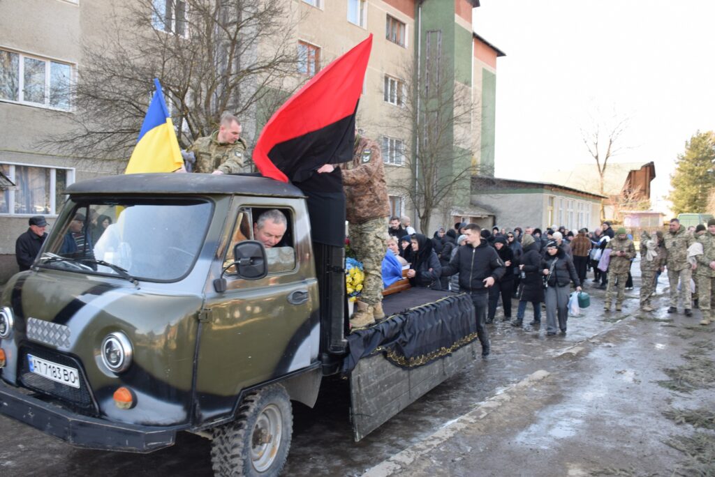 Люди біля військового автомобіля з прапорами