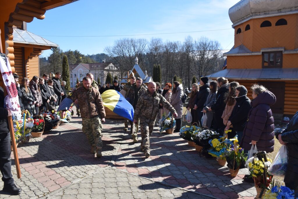 Похоронна процесія з українським прапором і квітами