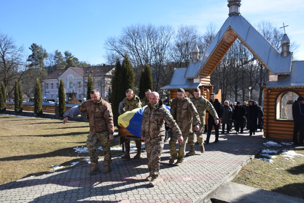 Військові несуть труну з прапором України.